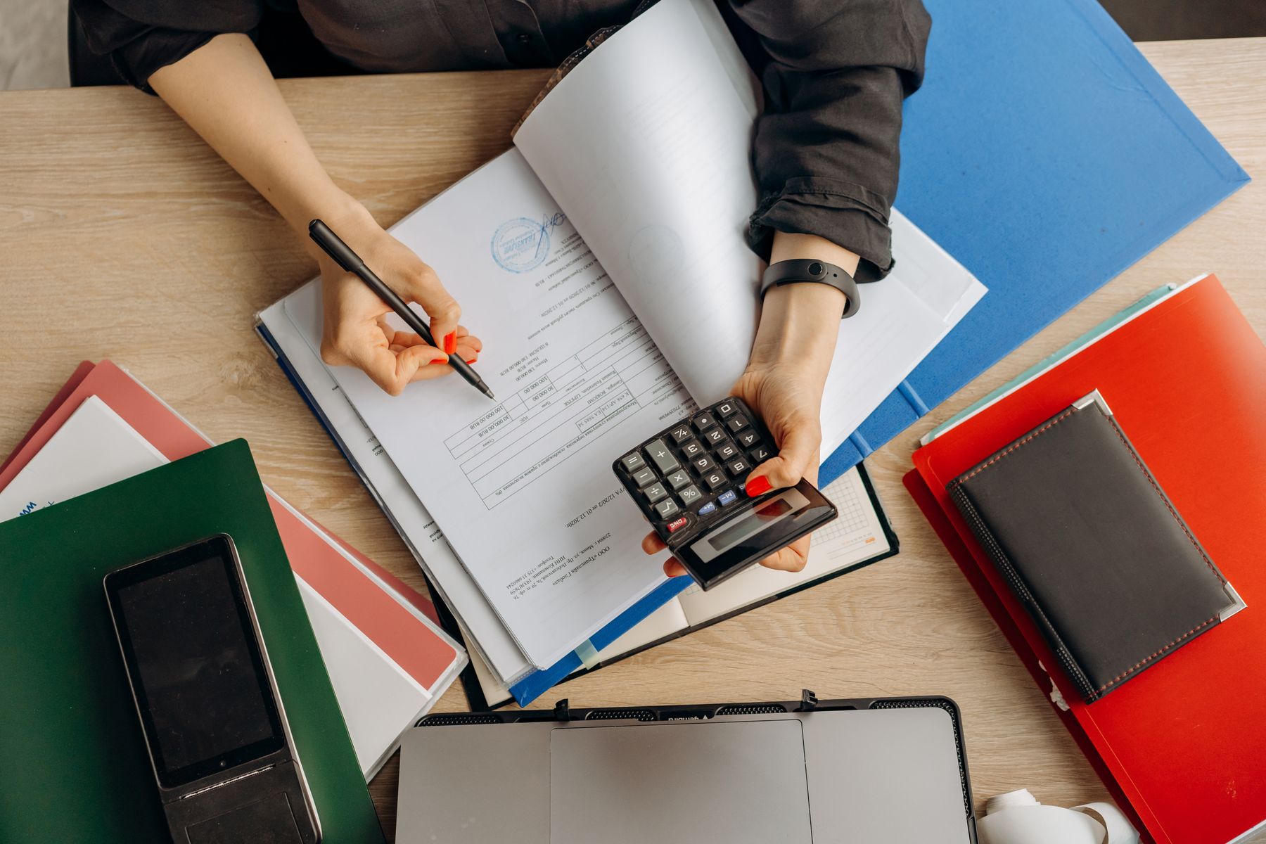 Profissional analisa documentos financeiros com uma calculadora